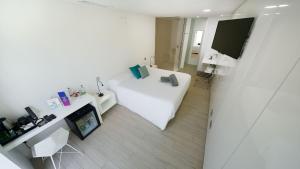 a white room with a bed and a tv at Seven Hotel & Wellness - Gay Men Only in Maspalomas