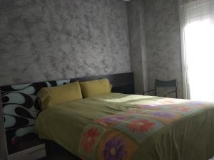 a bedroom with a bed with a colorful comforter and a window at EL RINCONCITO De DON DIEGO in Haro