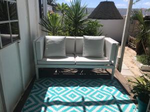 a white couch sitting on a porch with a rug at Trailer Beach Front Cottage in Savaneta