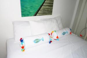 a white bed with two pillows with a fish on it at Apartment Brazil Beach Front Paradise in Savaneta