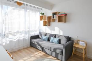 a living room with a gray couch and a window at Studio Carnon, plage, port et commerces à 2 pas in Carnon-Plage