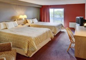 a bedroom with a bed, chair and a window at Lakeview Gimli Resort in Gimli