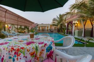 a table and chairs with a table and a pool at B-LBAIT Yanbu Villa Garden in Madīnat Yanbu‘ aş Şinā‘īyah +29 photos
