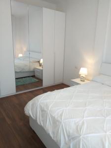 a white bedroom with a large bed and a mirror at Sesto Calende Centro in Sesto Calende