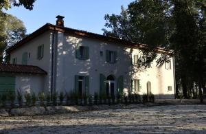 un grand bâtiment blanc avec des arbres en arrière-plan dans l'établissement Villa Il Selvatico, à San Giorgio di Piano