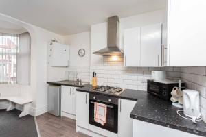 una cocina con armarios blancos y encimeras negras en Cherry Property - Orange Suite, en Blackpool