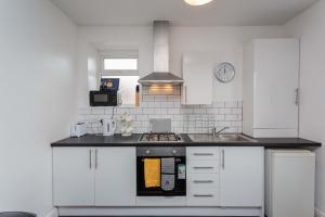a kitchen with white cabinets and a stove top oven at Cherry Property - Pineapple Suite in Blackpool