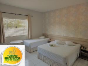 a hotel room with two beds and a window at Hotel Mandino in Lucas do Rio Verde