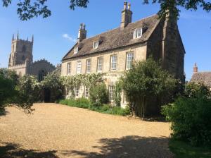 an old stone building with a church in the background at Teigh Old Rectory in Oakham