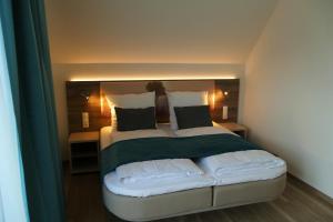 a bedroom with a large bed with green and white pillows at Meyn's Apartments & Hotel in Soltau