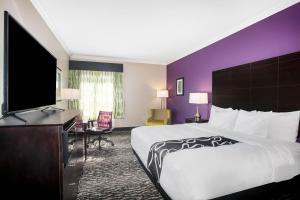 a hotel room with a large bed and a flat screen tv at La Quinta by Wyndham Houston - Magnolia in The Woodlands