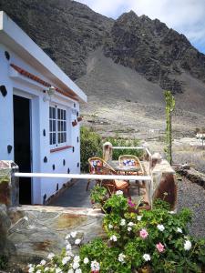 una casa con un porche con 2 sillas y flores en La Casita de la Breña., en La Frontera