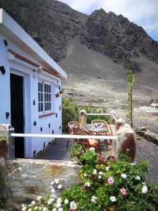 a house with a porch with two chairs and flowers at La Casita de la Breña. in Frontera