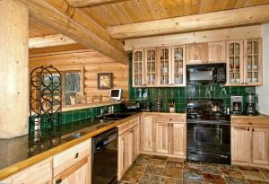 - une cuisine avec des placards en bois et une cuisinière noire dans l'établissement Hideaway Cabin, à Breckenridge