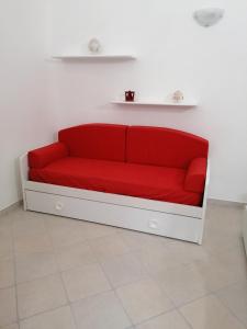 um sofá vermelho sentado num quarto branco em Casetta Carlotta em Ostuni