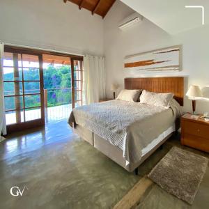 um quarto com uma cama e uma grande janela em Pousada Golf Village em Itaipava
