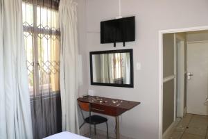 a room with a desk and a television on the wall at Bentley Lodge & Lifestyle in Durban