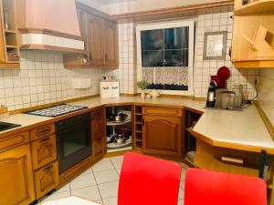 a kitchen with wooden cabinets and red chairs in it at Großes Ferienzimmer Uckermark in Casekow