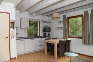 cocina con armarios blancos y mesa de madera en Basic vakantiehuisje op val d'Or, en Enscherange