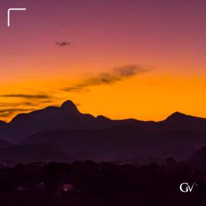 an orange sunset with mountains in the background at Pousada Golf Village in Itaipava