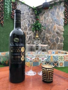 una botella de vino y dos copas de vino en una mesa en Cosmos Chill - Suite con jacuzzi y acuario en Ambato