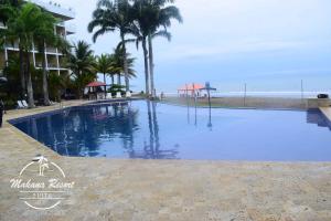 a swimming pool next to a beach with palm trees at Suite Makana #403 in Tonsupa