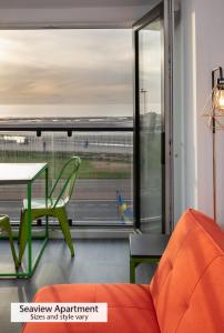 a living room with an orange couch and a table and a window at ApartHotel421 by Seafront Collection in Blackpool