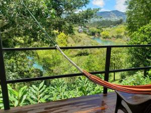 a hammock on a deck with a view of a river at Cabaña Manalí in Guatapé