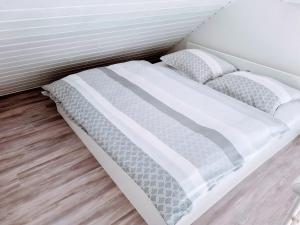 1 cama con sábanas blancas y almohadas en una habitación en Apartmán 1+1 s vlastním vchodem v Jeseníkách, en Vrbno pod Pradědem