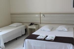 2 Betten in einem Hotelzimmer mit Handtüchern darauf in der Unterkunft Hotel Galead in Santa Bárbara dʼOeste
