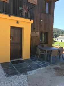 un patio con mesa y sillas junto a un edificio en El Refugio deI Sol La Fontarica & Fuente, en Trevías