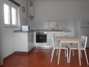 a kitchen with a wooden table and chairs in it at Studio Bibi in Gouvinhas