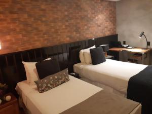 a hotel room with two beds and a brick wall at Hotel Heritage in Sao Paulo