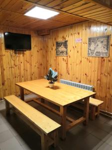 a wooden table and benches in a room with a television at Hotel Pioner 32 in Bryansk