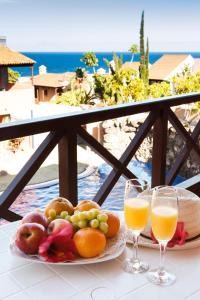 un tavolo con un piatto di frutta e due bicchieri di succo d'arancia di Aparthotel El Cerrito a Los Cancajos