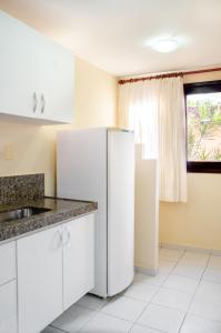 a kitchen with a white refrigerator and a window at Pousada Vale do Sul in Natal