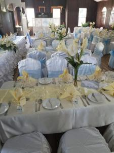 a dining room with white tables and chairs with flowers at Gem Holiday Beach Resort in Saint Georgeʼs