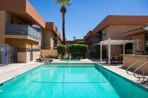 einen Pool in einem Apartmentkomplex mit einer Palme in der Unterkunft Palm Springs Sunrise Condo in Palm Springs