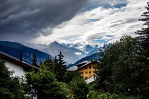 a view of a mountain range with a building and trees at My cozy escape in Crans-Montana