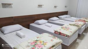 a group of four beds in a room at Flat familiar com ar,wi fi,cozinha e garagem in Aparecida