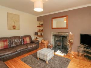 a living room with a leather couch and a fireplace at Feagour in Ardverikie