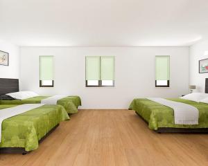 Asakusa HomeSuites Tokyo في طوكيو: أربعة أسرة في غرفة بجدران بيضاء وأرضيات خشبية