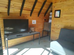 a living room with a large television in a wooden wall at Glamping Los Ángeles in Guasca