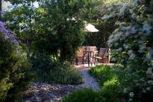 a table and chairs in a garden with an umbrella at Donnybrook Cottages - Hutt River in Clare