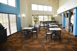 a dining room with tables and chairs and windows at Baymont by Wyndham Santee in Santee