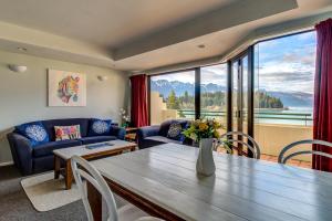 a living room with a table and a large window at Lakefront Apartments,18 LAKE ESPLANADE ROAD in Queenstown