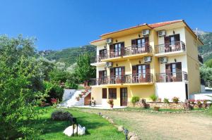 a large yellow building with balconies and a yard at Pension Sotiria in Koinyra
