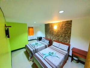 two beds in a room with green walls at Aosmec Square Hotel in Mactan