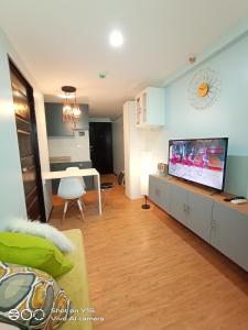 een woonkamer met een flatscreen-tv en een tafel bij A cozy 1 br Scandinavian inspired condo unit near the beach in Davao City