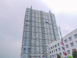 a tall white building with a street light in front of it at Simply Look Studio Tamansari Mahogany Karawang Apartment By Travelio in Karawang